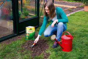 Frau sät kahle Stellen im Rasen mit Rasenreparatur LückenLos nach